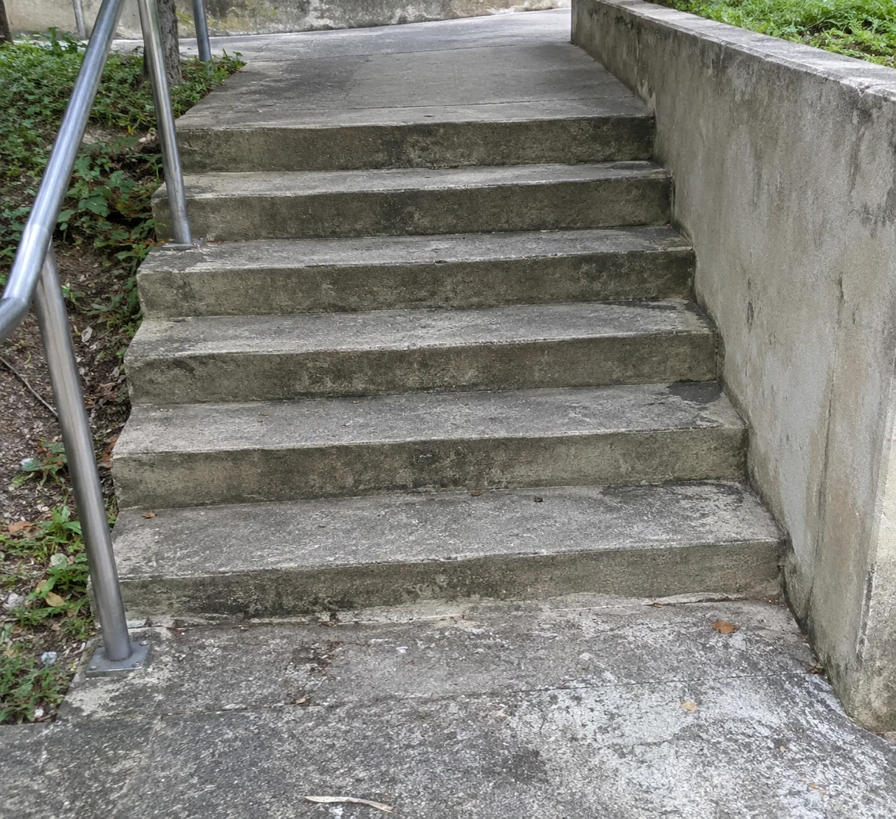 A short flight of empty concrete stairs with a plain handrail.